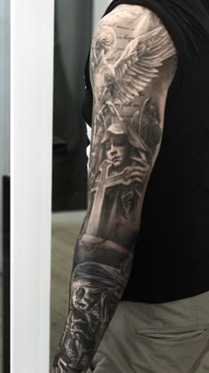 a man with a black and grey tattoo on his arm is standing in front of a mirror