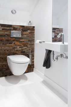 a white toilet sitting next to a sink in a bathroom under a mirror and towel dispenser