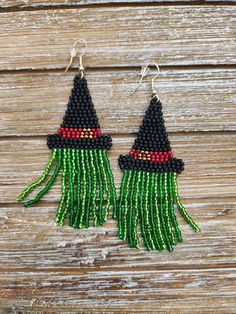 green and black beaded witch earrings on wooden background