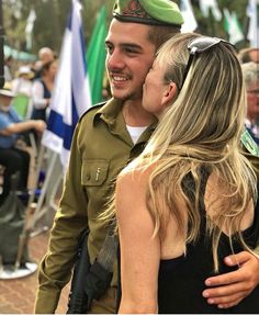 a man in uniform is hugging a woman who is wearing a green beret on her head