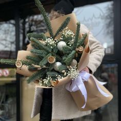 a woman holding a bouquet of flowers in front of a storefront with christmas decorations on it