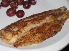 a white plate topped with fish and grapes