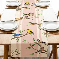 the table is set with white plates and placemats, which have birds on them