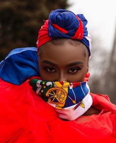 a woman in red and blue is wearing a colorful head piece with an elaborate scarf around her neck