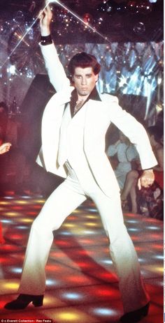 a man in white suit and tie dancing on stage