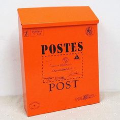 an orange post box sitting on top of a white table