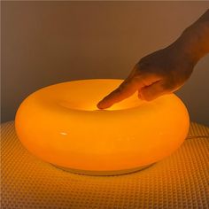 a person touching an illuminated object on top of a round table with a hand pointing at it