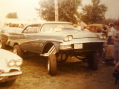 an old photo of cars parked in a lot with people looking at them and taking pictures