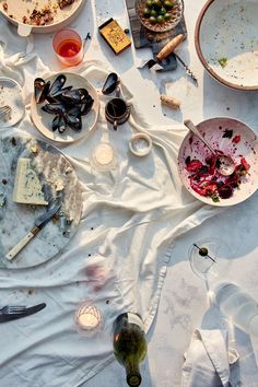 the table is covered with dirty dishes and empty wine glasses, plates, utensils