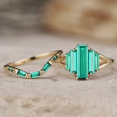 an emerald colored ring sitting on top of a rock