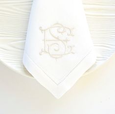 a white plate with a monogrammed napkin on it