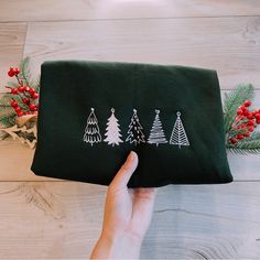 a hand holding a green bag with christmas trees on it