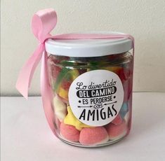 a jar filled with lots of colorful candies next to a pink ribbon on the side