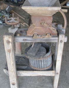 an old fashioned machine sitting on top of a wooden stand next to other tools and materials