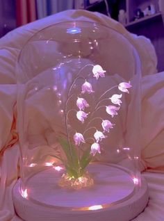 a glass dome with flowers in it on a bed