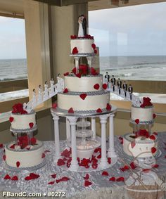 the wedding cake is decorated with red roses and white icing, along with two tiered cakes