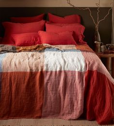 a bed with red pillows and blankets on it