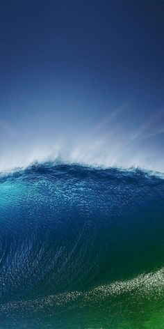 a man riding a wave on top of a surfboard under a blue cloudy sky