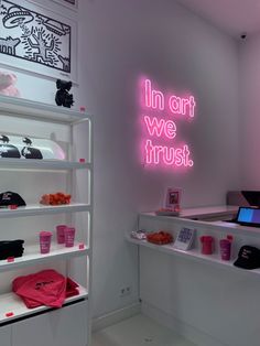 a pink neon sign that says in art we trust on the side of a wall