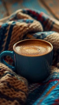 a cup of coffee sitting on top of a blanket