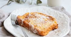 a piece of cake on a plate with a fork and glass of milk next to it