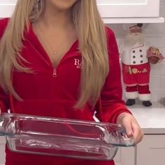 a woman in a red dress is holding a glass casserole dish