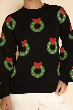 a woman wearing a black sweater with christmas wreaths on it