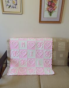 a pink and white crocheted blanket sitting on top of a couch