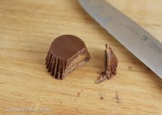 a knife is next to a piece of chocolate cake on a cutting board with it's end cut off