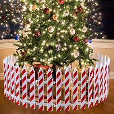 a christmas tree with candy canes in front of it and a fence around it