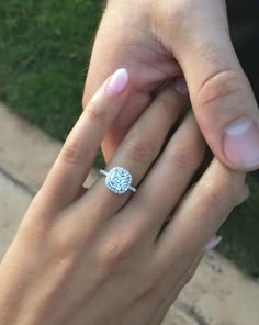 a close up of a person's hand with a diamond ring on their finger