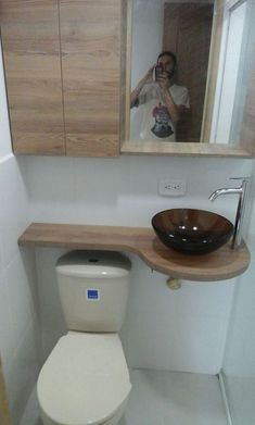 a man taking a selfie in the mirror of a bathroom with a sink and toilet