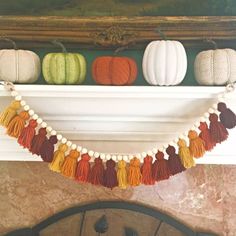 a mantle decorated with pumpkins and tassels for fall decor in a living room