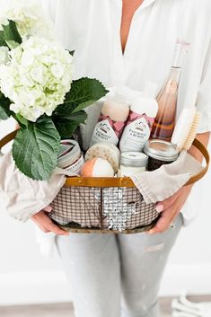 a woman holding a basket full of personal care products and flowers in it's hands