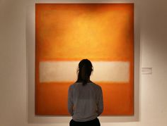 a woman standing in front of an orange and white painting