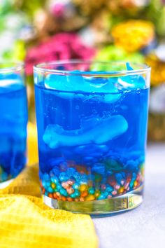 two glasses filled with blue liquid on top of a table