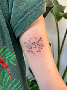 a small tattoo on the arm of a person with a teddy bear and angel wings