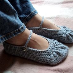 a woman's feet wearing crocheted slippers on top of a bed