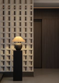 a lamp sitting on top of a black table next to a white wall covered in squares