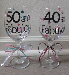 two wine glasses with bows on them sitting next to each other in front of a wall