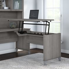 a computer desk with a laptop on it in front of a bookcase and bookshelf