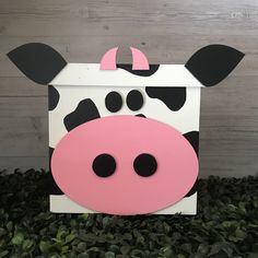 a cardboard cow head sitting on top of some green plants