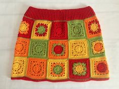 a colorful crocheted skirt is displayed on a white tablecloth with an orange, green, yellow and red pattern