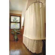 a bathroom with wood floors and a white shower curtain hanging from the side of the bathtub