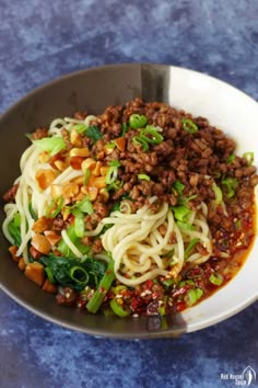 a bowl filled with noodles, meat and veggies on top of a table