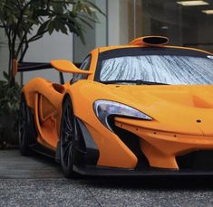 an orange sports car parked in front of a building