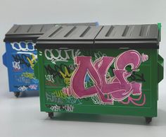 two trash cans with graffiti on them and one has the letter dxs painted on it