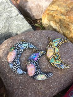 two pendants sitting on top of a rock next to some grass and rocks with stones in the background