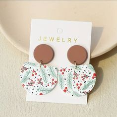 a pair of earrings sitting on top of a white plate next to a paper card