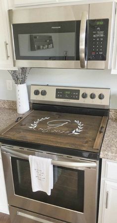 a kitchen with stainless steel appliances and white cabinets, including a microwave above the stove